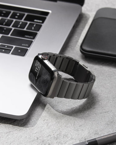 Apple Watch with a nomad titanium watch band leaning on a macbook pro
