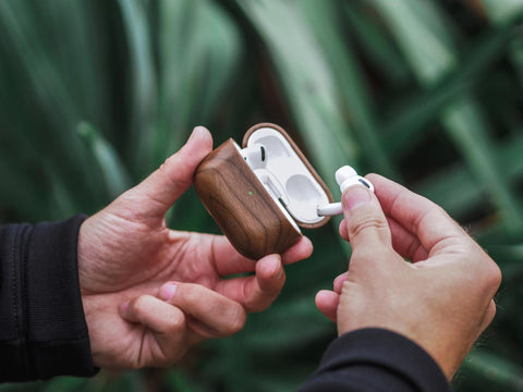 man taking out his airpods pro from his case which is protected by a woodcessories walnut wood case