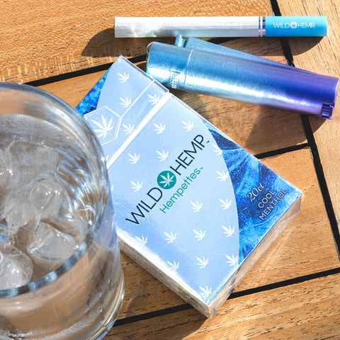 Menthol CBD Cigs next to a refreshing cup of ice water and a blue lighter.