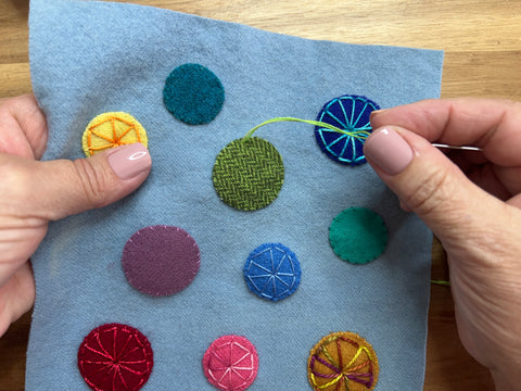 photo of a wool appliqué penny mat with needle on top for eyelet wheel stitch