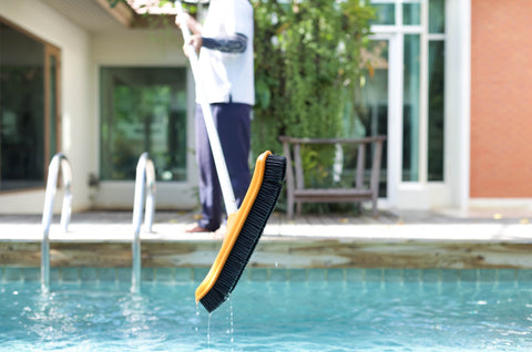 Brushing swimming pool sides and surface with pool brush