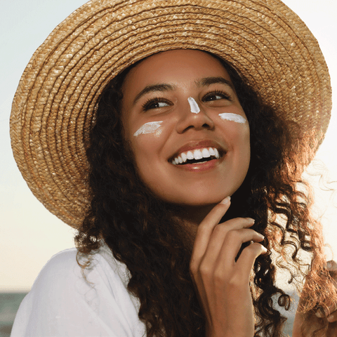 Smiling woman in sun hat with SPF on face