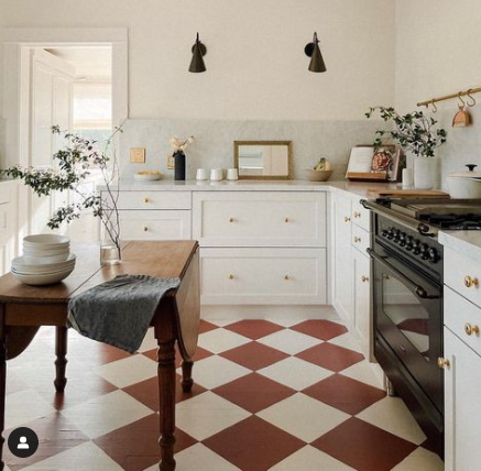 photo of a kitchen with pink tiled floors, wooden table and white cabinets