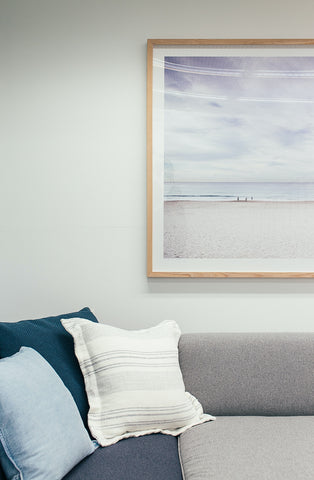 image of a couch with pillows with beach inspired wall art 