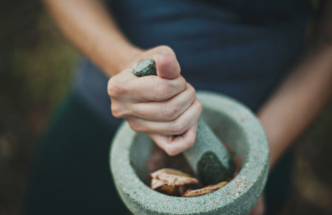 woman using mortar and pestle to grind herbs