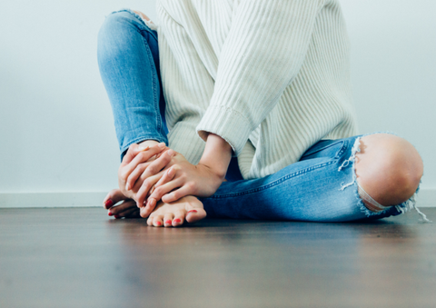 woman sitting barefoot on the floor with right knee up