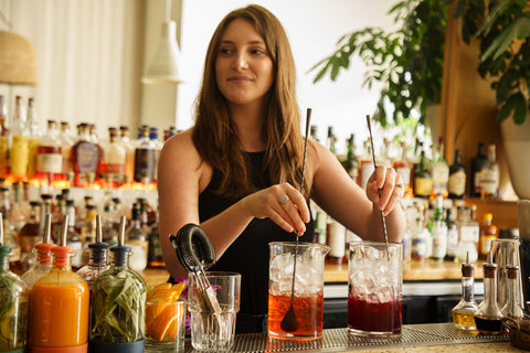Bartender Stirring Craft Cocktails Surrounded by Bar Supplies
