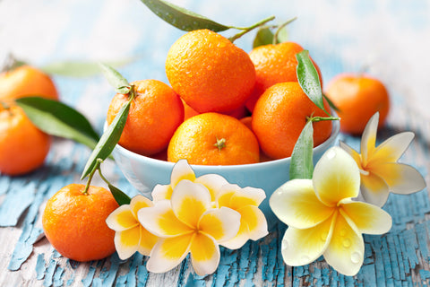 monoi flowers and oranges on blue table