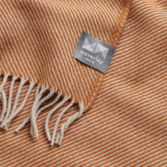 A close up image of a merino wool throw with a grey and tan diagonal stripe pattern.