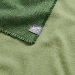 A close up image of a merino wool blanket in green.