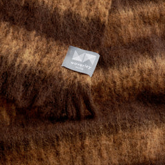 A close up image of an alpaca throw with light and dark brown alternating horizontal stripes.