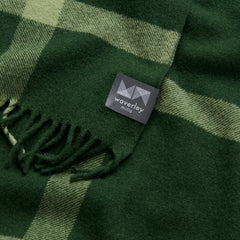 A close up image of a dark green blanket with lighter green stripes.