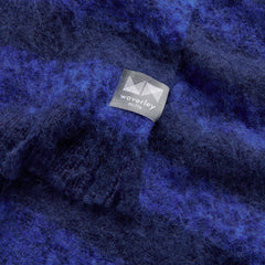 A close up image of an alpaca throw with cobalt blue and navy blue horizontal stripes.