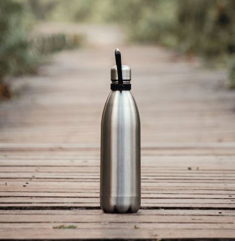 Metal water bottle sitting on a wooden pathway. 