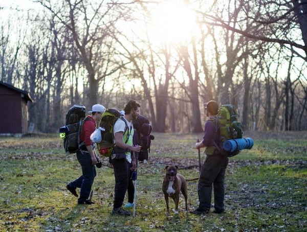 hunters hiking with large bags and bed rolls with their dog