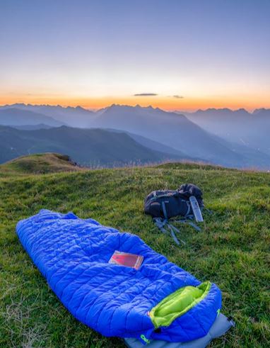 Sleeping bag on the top of the mountain looking out at a sunset.