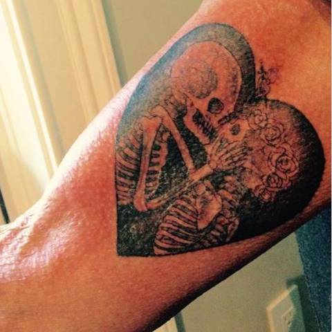 Tatouage de Johnny Hallyday représentant un couple de squelettes dans un cœur