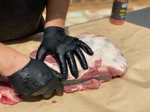 Trimming pork shoulder with black gloves