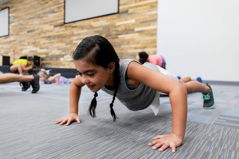 little girl doing push ups in gym class