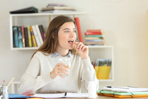 teen girl taking organic multivitamins while studying at home