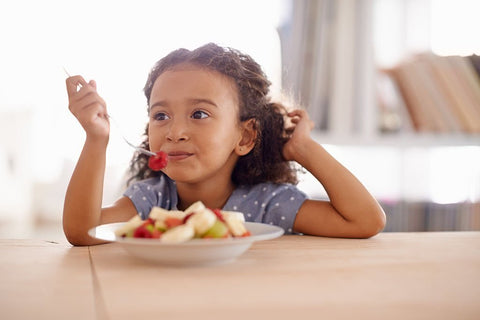 young girl kid eating fruit at table
