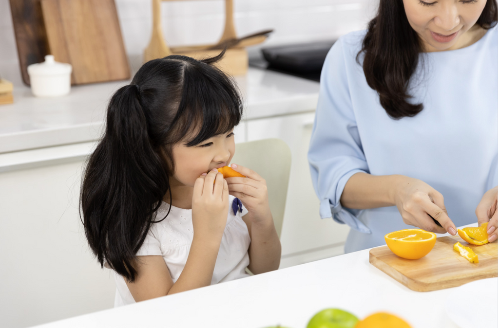 Happy family eating and slicing fruits oranges and apples