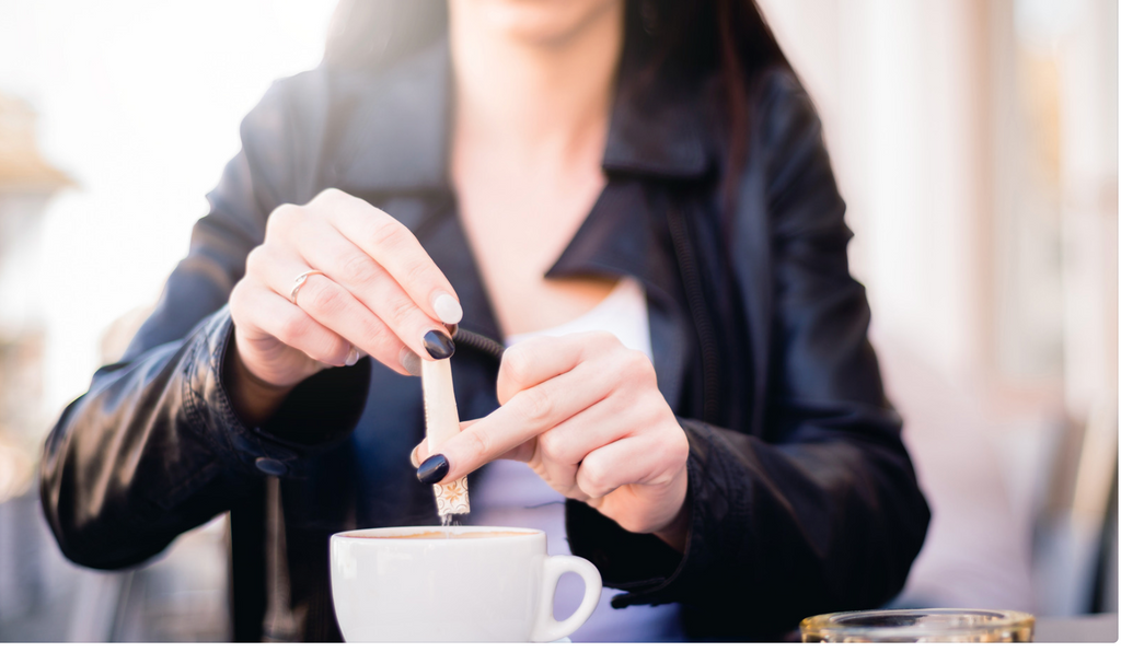 person putting sweetener in coffee