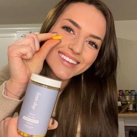 a woman holding up a single capsule from our joint support supplement