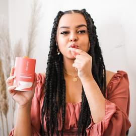 a woman smiling as she eats a womens supercharge gummy vitamin