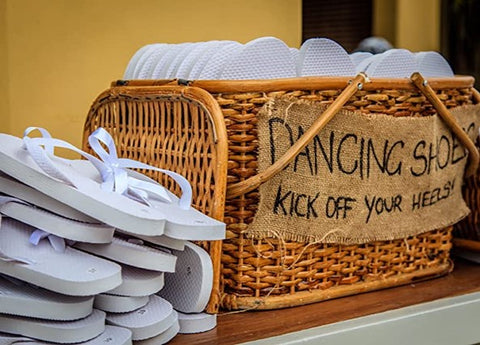 white flip flops displayed at a wedding reception with a sign that says "dancing shoes"