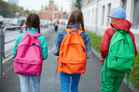 young students walking to school wearing colorful backpacks