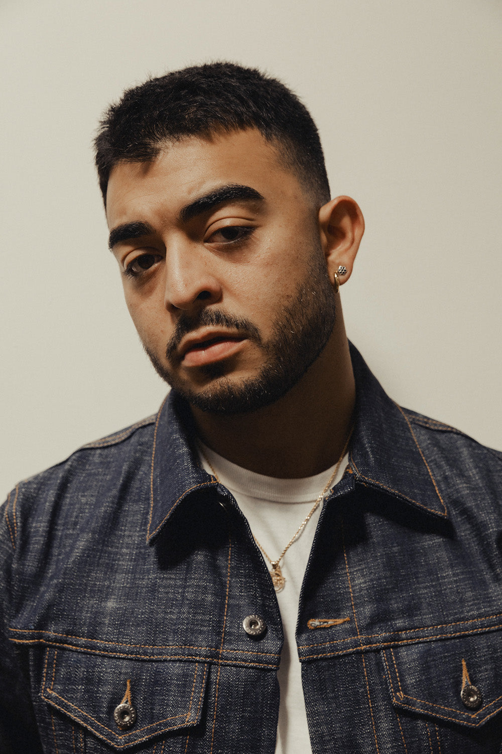 A close up portrait of a man in a denim jacket.