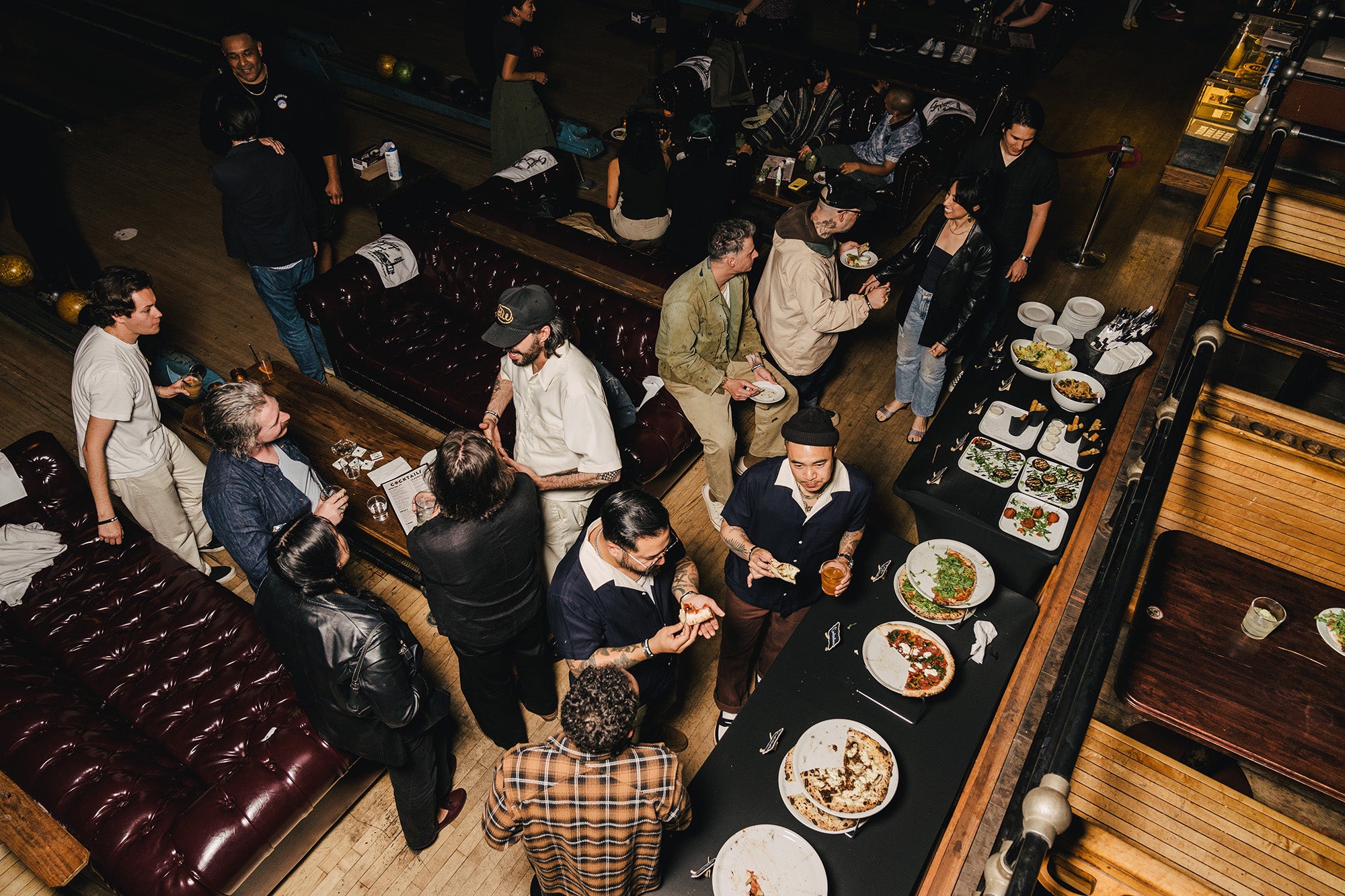 A large group of people in a bowling alley eating and drinking.