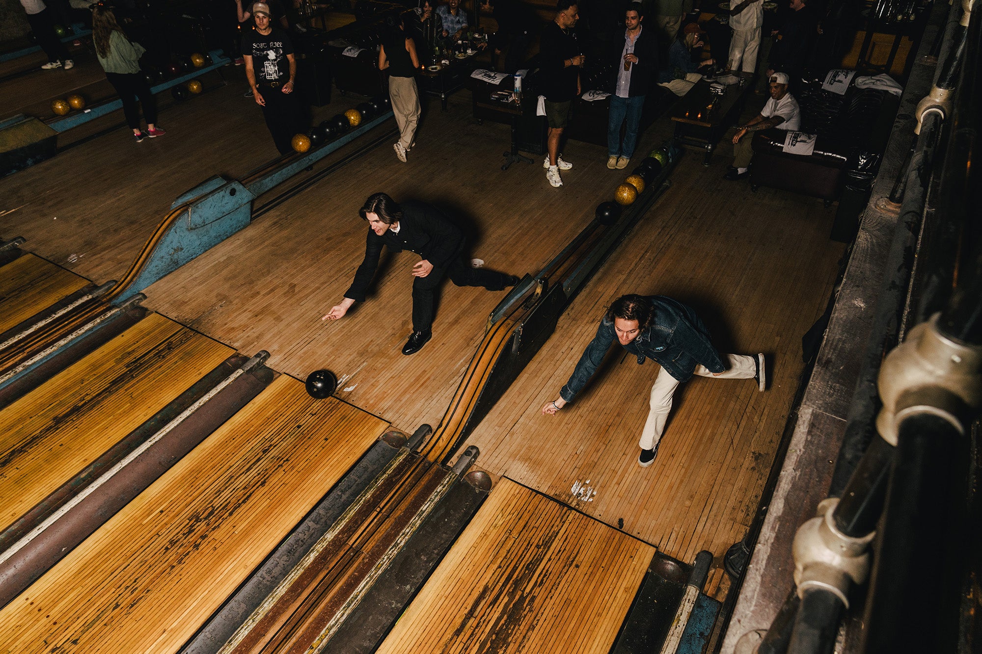 Two men bowl sychronously. 