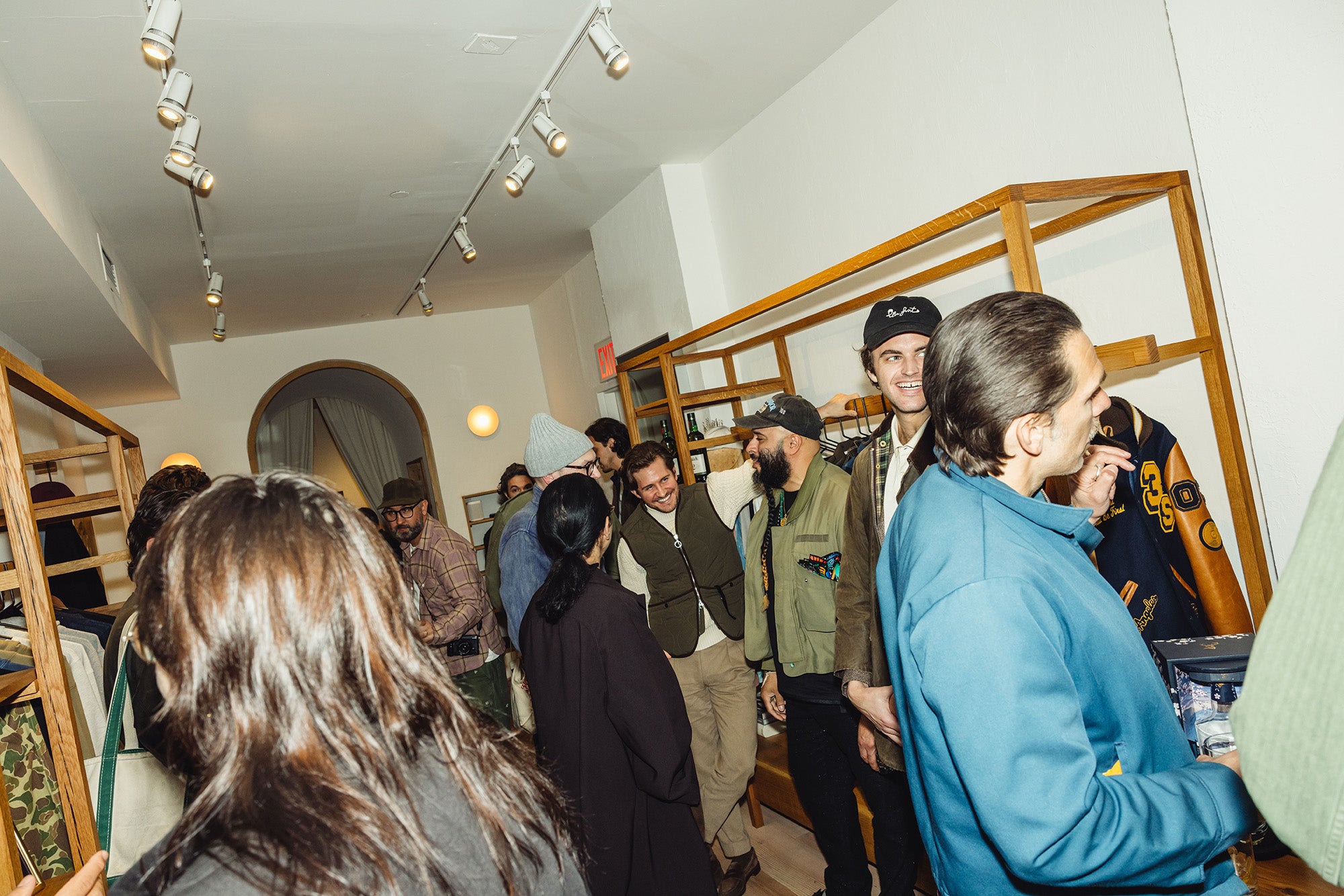 Many party attendees in a room with drinks and conversation