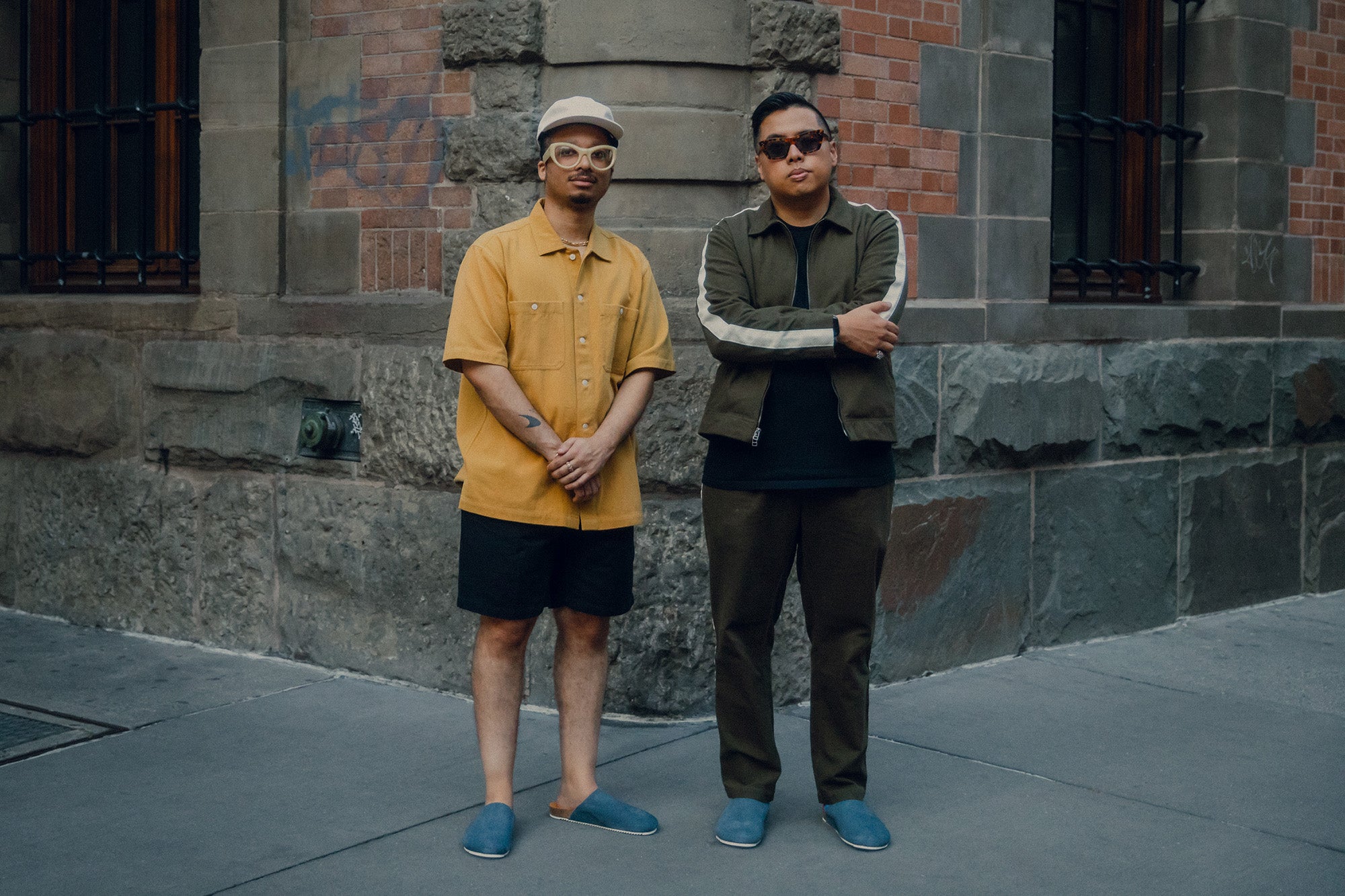 Two men in mules stand on the street.