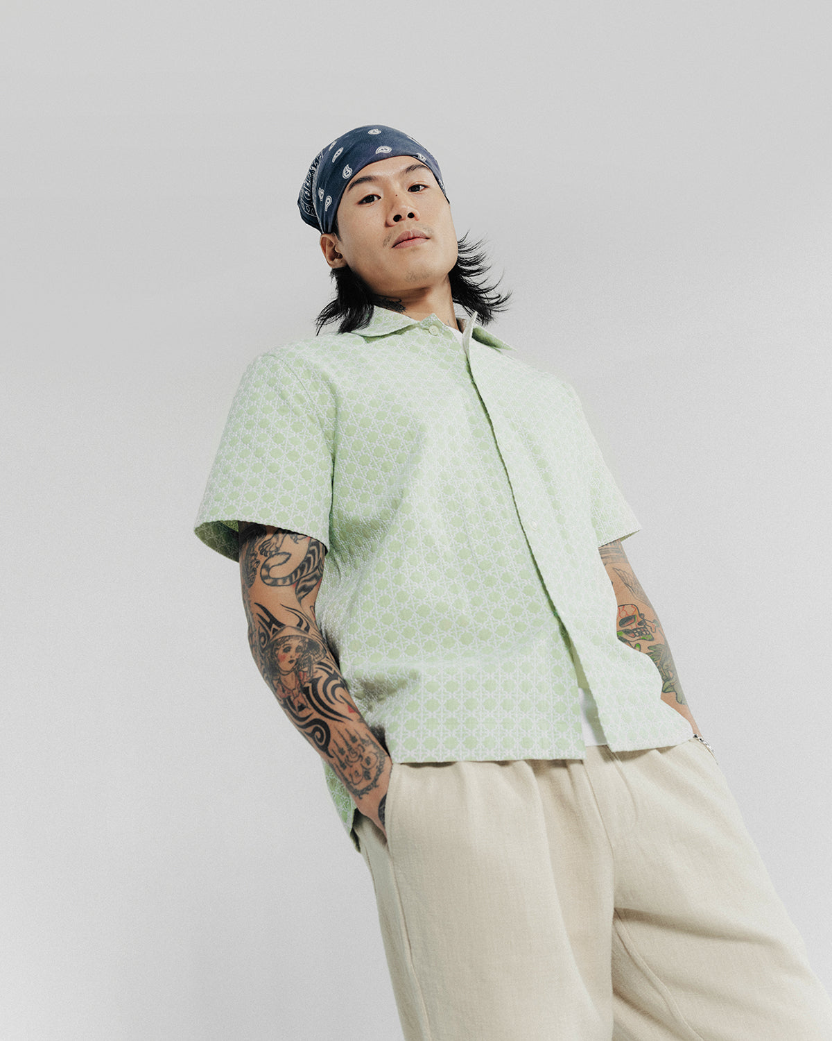 A man poses in a navy bandana and seafoam shirt.