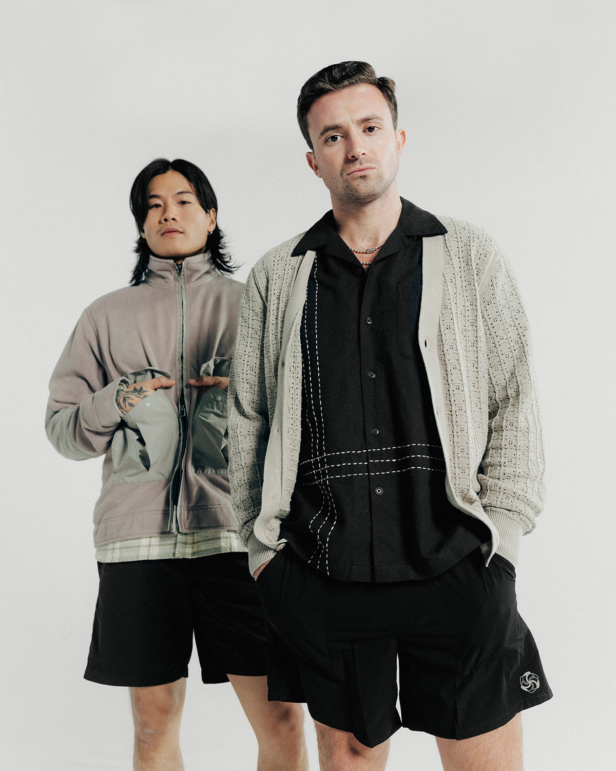 Two men pose in grey tops and black shorts.