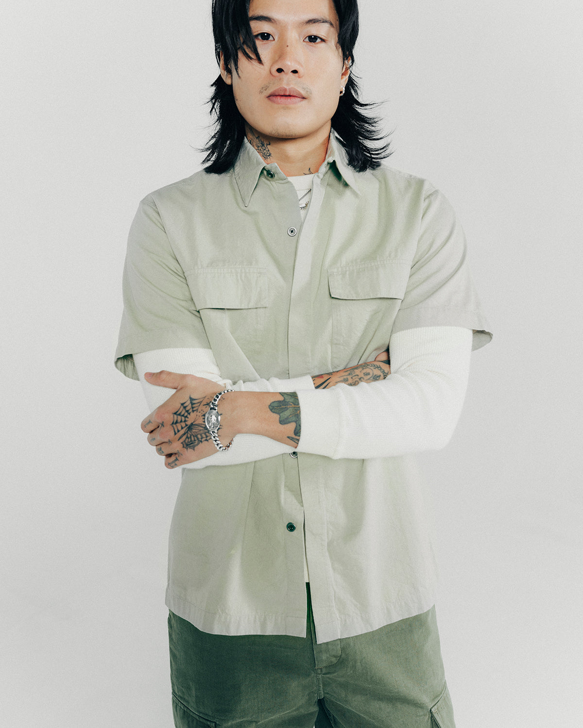 A man poses in a seafoam shirt layered over a thermal long sleeve tee.