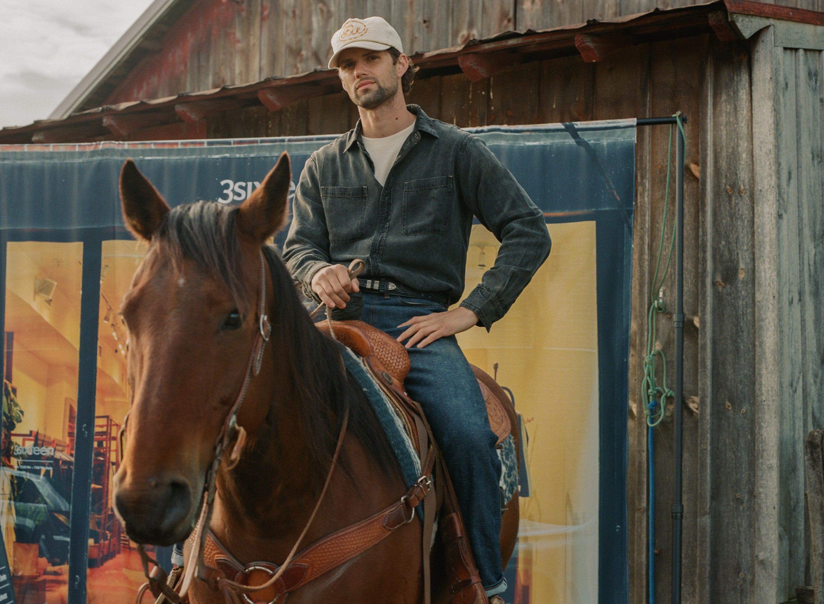 A man in a white hat, black shirt and blue jeans atop a horse.