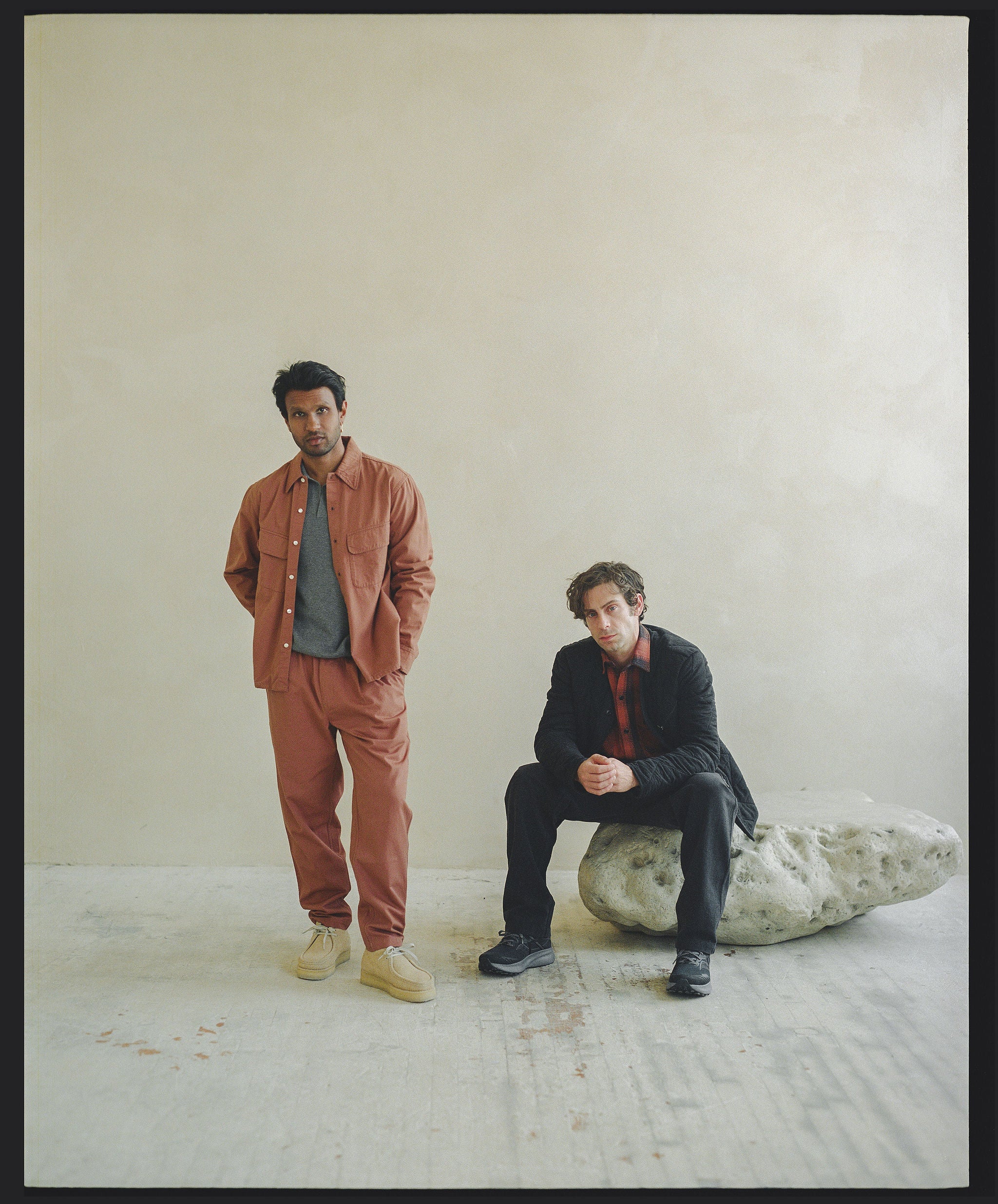 Two men - one in a matching orange suit and another in a black liner jacket and orange flannel.