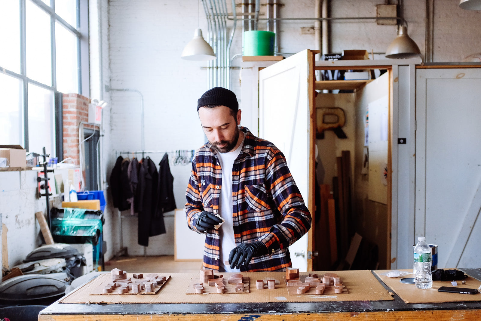 Man standing over table staining wood pieces.