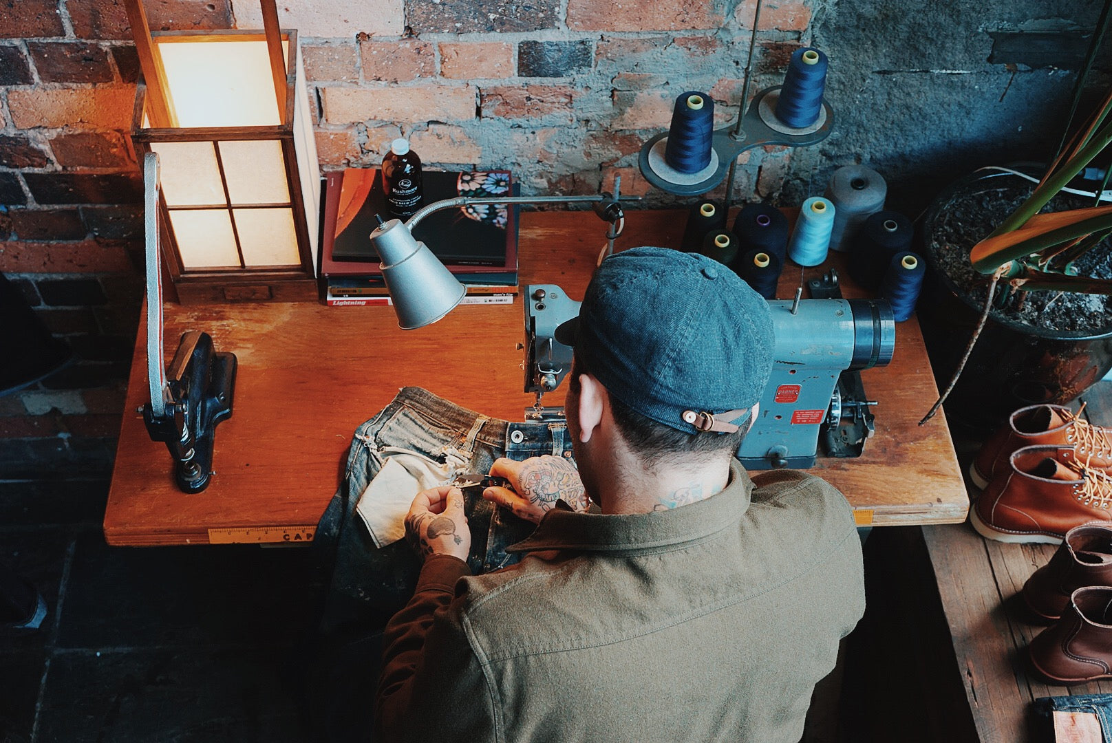 Man repairing jeans on sewing machine.