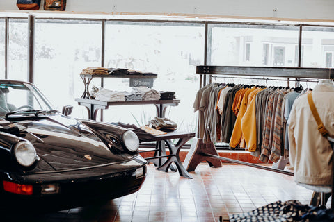 A view of the shop floor at Iron Shop Provisions with a vintage Porsche on the left and a rack of clothes on the right.