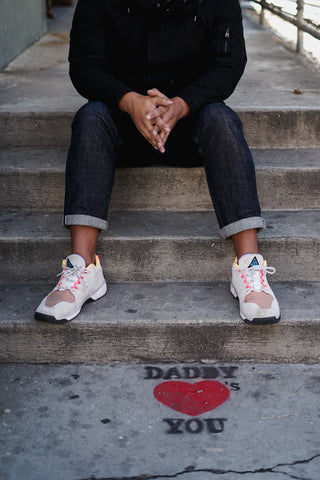 Roland sits on a staircase with some artwork sprayed onto the concrete floor stating "Daddy Loves You."