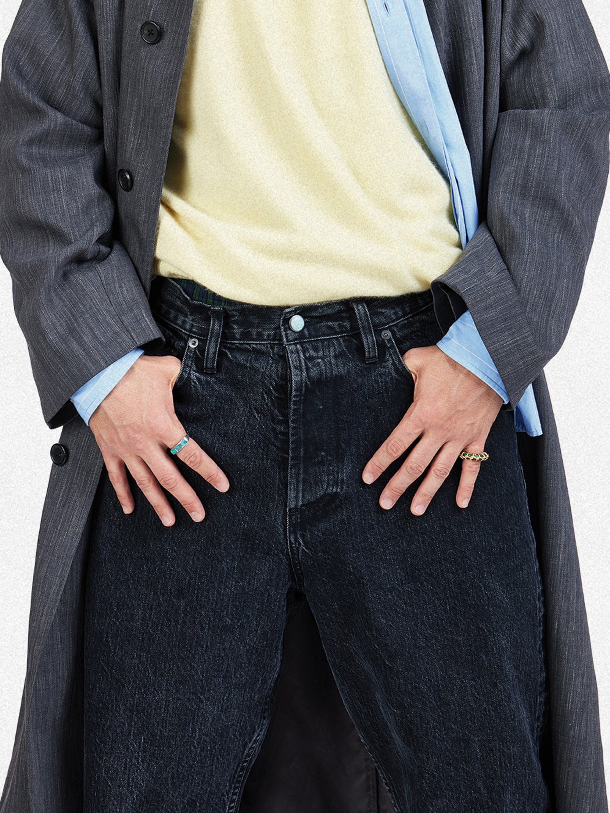 A close up detail of a man in black stonewashed jeans with hands in pockets.