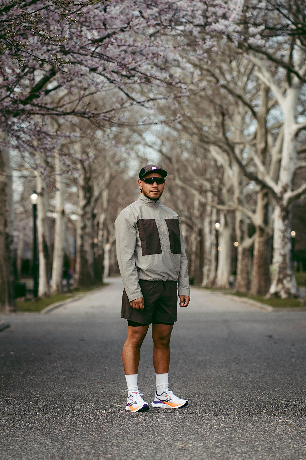 A man stands between blooming trees.