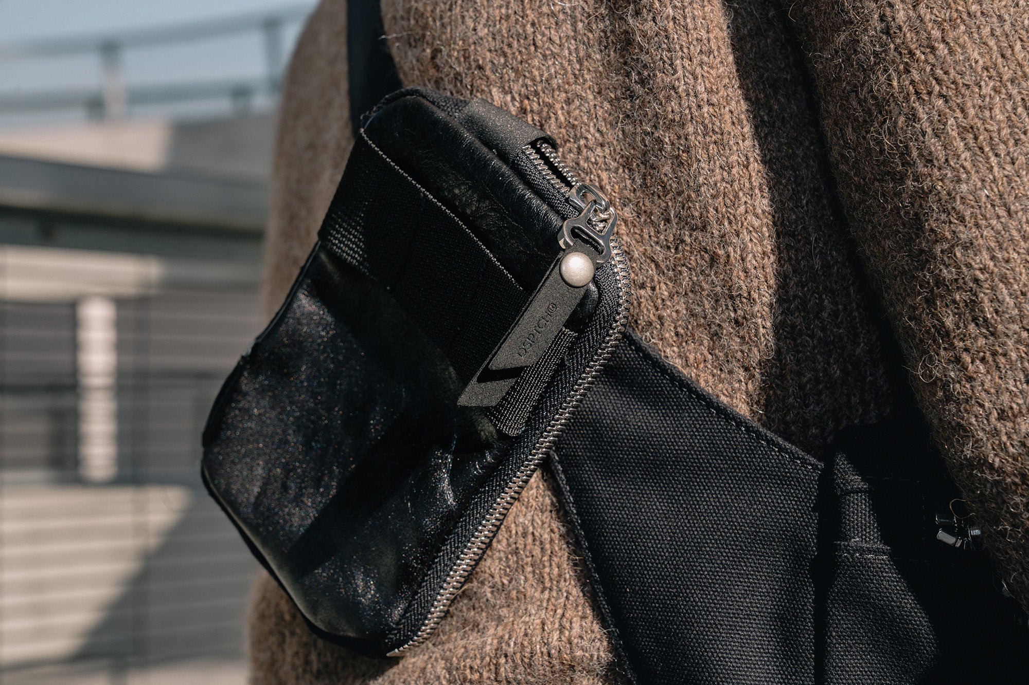 A close up view of a black leather pouch with metal zipper.