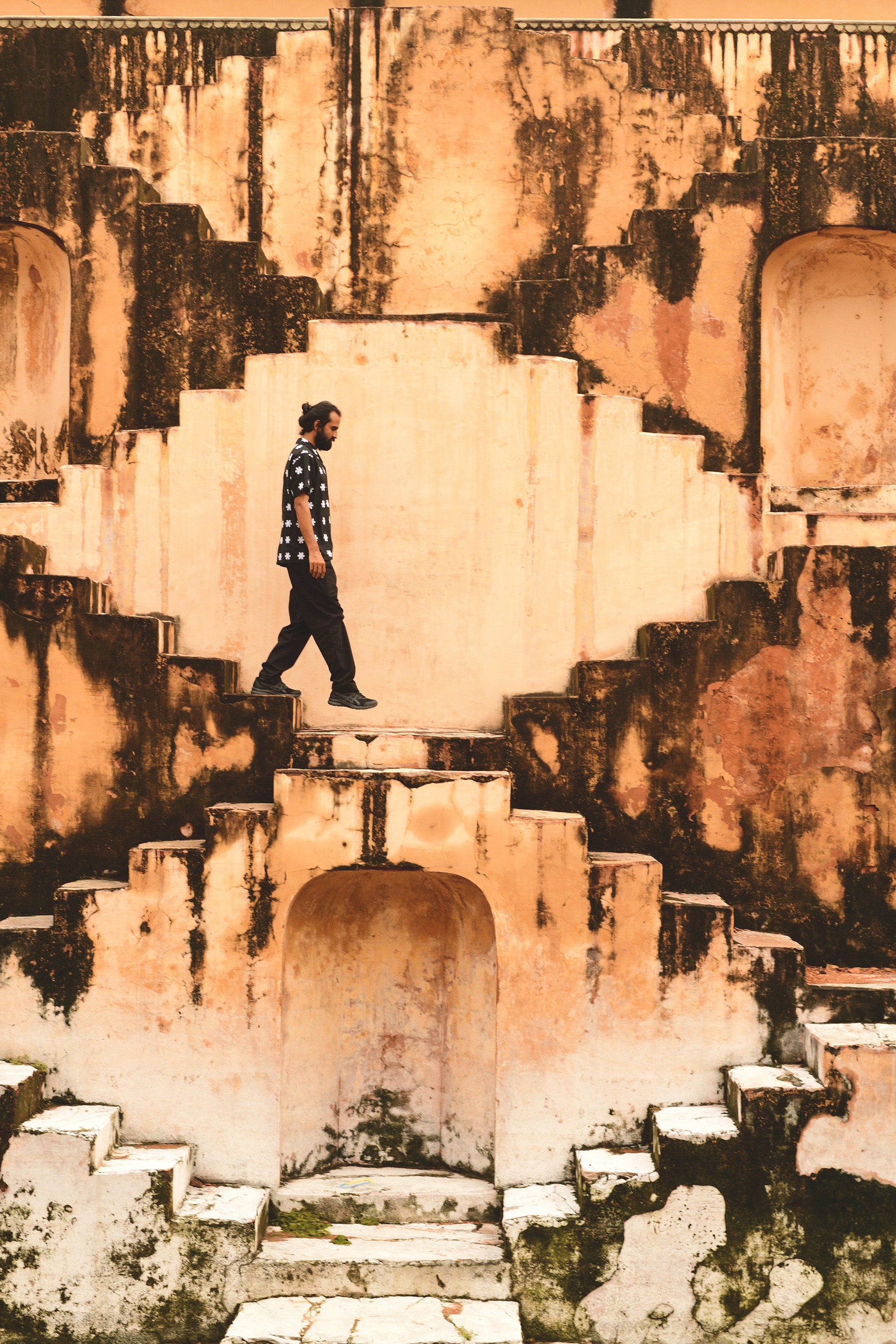 A man in black shirt and pants walks down stone steps.