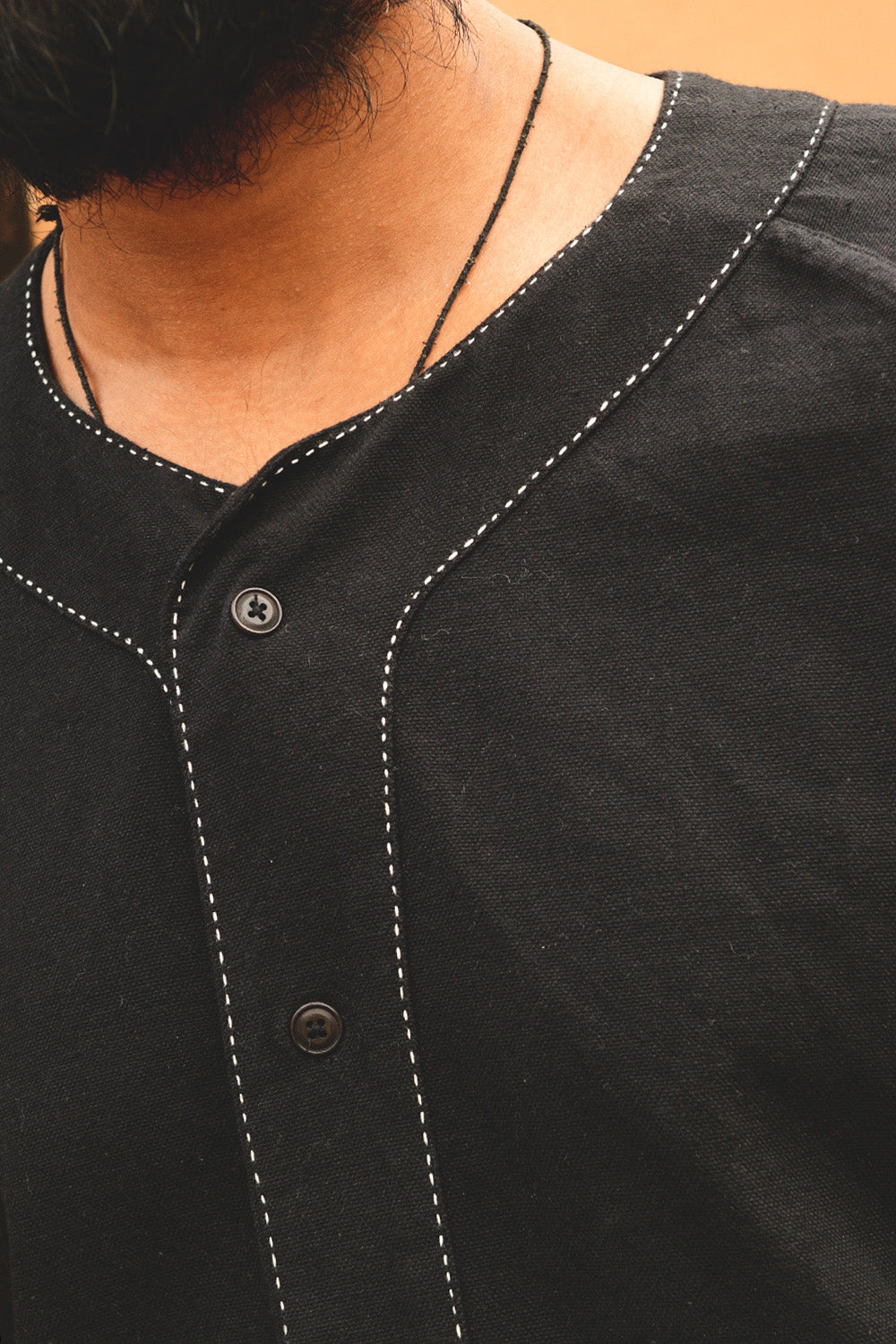 An up close detail photo of a black baseball shirt with hand stitching details.